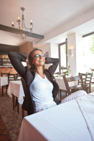 Portrait of a happy young woman sitting in a restaurantの写真素材