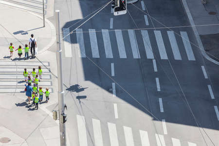 Some unrecognizable preschooler with their teachers crossing the street at a sunny dayの写真素材