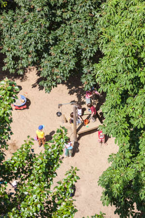 Aerial view of a sandy playground with some playing children surrounded by green trees.の写真素材