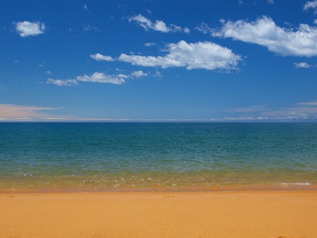 A tropical blue sea with golden sand beach and a perfect skyの写真素材