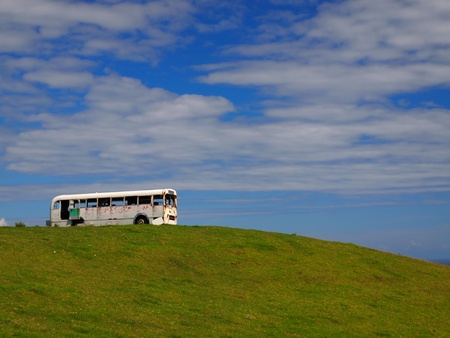 old bus taking the scenery in from the top of a hillの写真素材