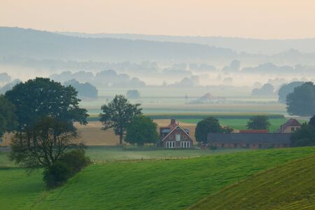 Sunrise over a misty farm in the hillsの写真素材