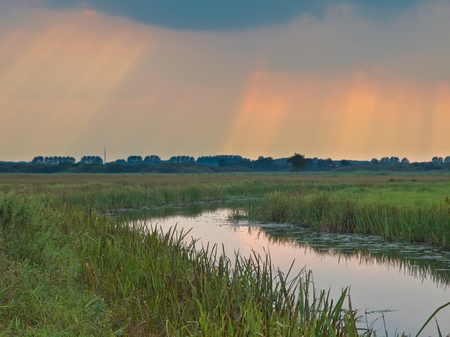 Sunrays are shining through the clouds above lowland river valleyの写真素材