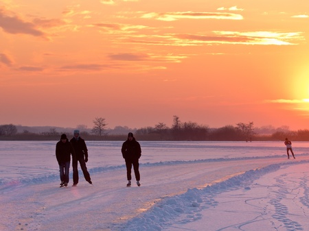Group of ice skaters during sunset on natural iceの写真素材
