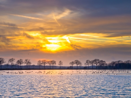 Spectacular sunset over half frozen lake in the netherlands in winterの写真素材