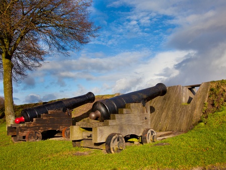 Two Old Cannons Behind a Dam in the Museum Fortress of Bourtange in the Netherlandsのeditorial素材