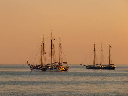 Vintage Sailing Ships in Orange Light during Sunset over IJsselmeer, The Netherlands