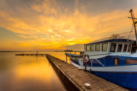 Boat on a jetty in a lake during beautiful orange sunsetの写真素材