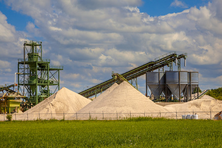 Industrial sand mining terminal with conveyer belts and silos on a clouded summer dayのeditorial素材