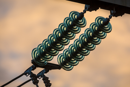 Powerline insulation disks against a orange sky during sunsetの写真素材