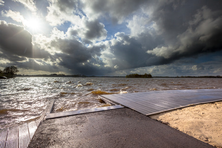 Strong wind dark clouds and moderate high waves breaking on a landing stage when a storm is coming...