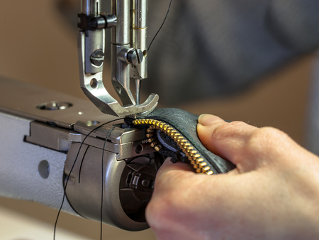 Leather sewing machine in action with hands working on a shoulder bagの写真素材
