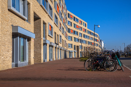 Modern apartment block with light bricks and orange sun screens in a suburban neighbourhood with bicycles parked in frontのeditorial素材