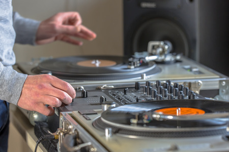 Hands of DJ mixing music from vintage long play  records in his studio at homeの写真素材