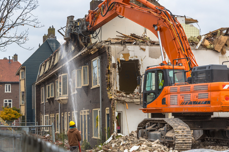 Orange Demolition crane demolishing old row of houses in the Netherlandsの写真素材
