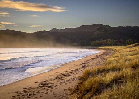Sunrise over the Ocean Waves on the beach of Waikawau Bay Beach New Zealandの写真素材