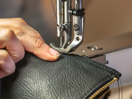 Sewing machine in action in workshop operated with hands working on garment