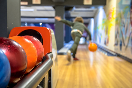 Child throwing bowling ball on indoor bowling alleyの写真素材