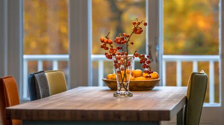 Autumn interior still life scene with red berries, oranges and yellow foliage background