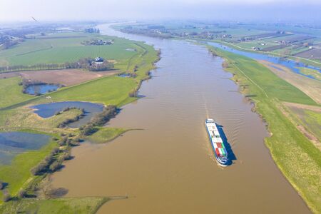 Inland container barge on River Lek aerial view near the village of Ravenswaaij, Gelderland, Netherlandsの写真素材