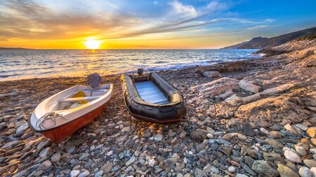 Two boats at sunset on a pebble beach on Cap Corse, Corsica, France.の写真素材