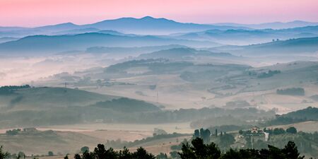 Tuscany hilly landscape scene with early morning haze over village countryside
