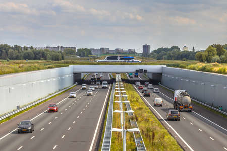 Afternoon traffic on a4 motorway near The Hague Randstad area. Highway crossing aqueduct tunnel with...