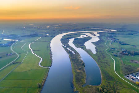 Aerial view of huge lowland river through sunset landscape.の写真素材