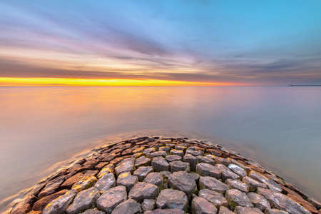 Typical basalt breakwater pier construction at  IJsselmeer near the town of Hindeloopen in the Friesland Province at sunset, Netherlands.の写真素材
