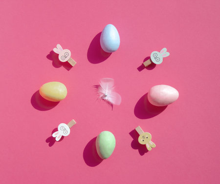 Clock made of Easter eggs and bunnies on pastel pink background. Easter time 2021. Creative flat lay.の写真素材