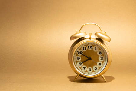 Golden vintage alarm clock on illuminating background with copy space. Monochromatic retro composition.の写真素材