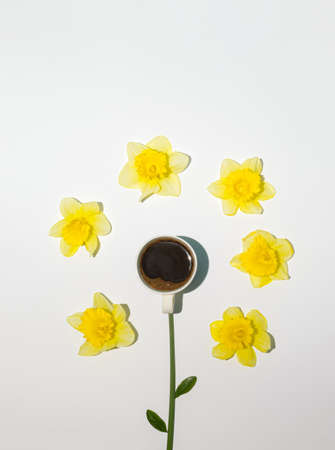 Coffee cup and yellow daffodils on illuminating background. Minimal spring concept. Flat lay.の写真素材