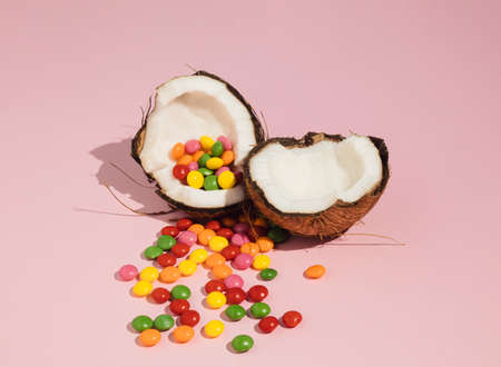 Coconut cracked in half and colorful candy. Minimal summer idea. Creative food concept.の写真素材