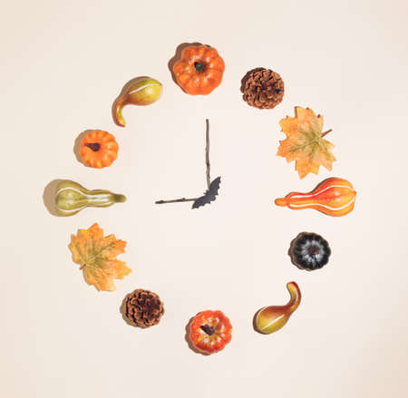 Creative autumn clock made of colorful autumn leaves, pumpkins and pinecones. Nature mockup background. Seasonal concept. Flat lay wreath.の写真素材