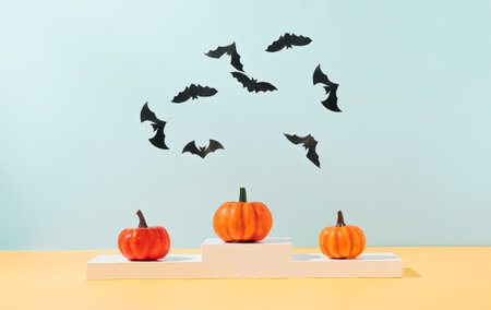 Creative concept made of colorful autumn pumpkins standing on winning podium and bats silhouettes. Trendy Halloween background. Modern aesthetic.の写真素材