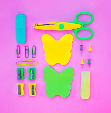 Neatly arranged pattern made of wooden pencils on pink background with school supplies. Creative flat lay, top view. Back to school concept with stationery.の写真素材