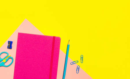 School pink notebook and various stationery on yellow background. Back to school concept. Flat lay, top view, copy space.の写真素材