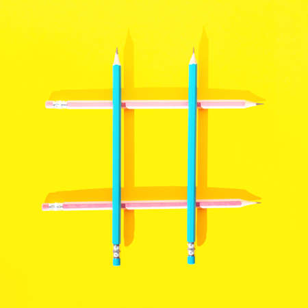 Four wooden pencils on yellow background assembled in a shape of hashtag. Top view, flat lay. School concept. Social media or marketing idea creative concept. Contemporary business artistic design.の写真素材