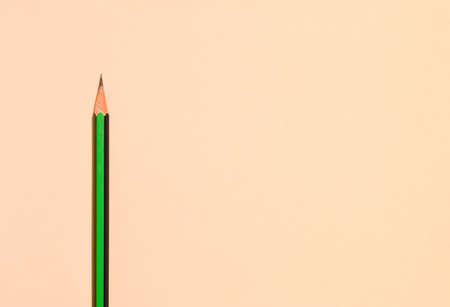 Wooden pastel green pencil on beige background. Back to school concept. Top view, flat lay, copy space.の写真素材