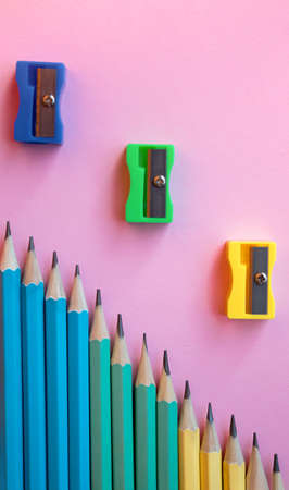 Colored wooden pencils and pencil sharpener on pink background. Top view, flat lay. Back to school, education concept.の写真素材