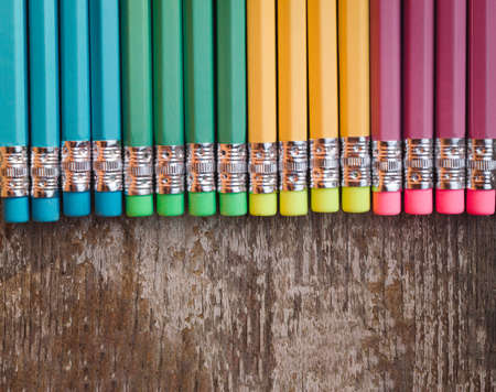 Colored pencils with erasers on wooden background. Top view with copy space. Flat lay. Back to school, education concept.の写真素材