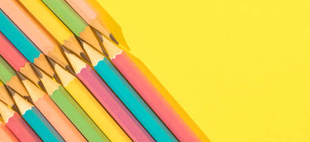 Colored wooden pencils on yellow background. Top view with copy space. Flat lay. Back to school concept.の写真素材