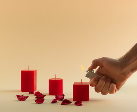 Romantic composition with red candles, man's hand and petals on bright beige background. Valentines Day concept. Copy space.の写真素材