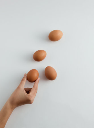 Hand is holding Easter egg. Eggs on white background. Minimal food concept. Top view, flat lay.の写真素材