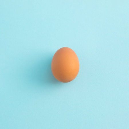 Uncooked egg on pastel blue background. Minimal food concept with copy space. Top view, flat lay.の写真素材