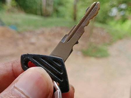 Close-up of a hand holding a motorcycle key in a symbolic gesture, representing ownership, freedom,...