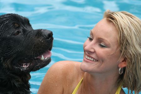 Woman swimming with rottweiler in poolの写真素材