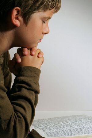 Young boy praying over the bibleの写真素材