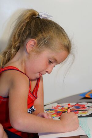 child coloring on paper sticking out tongueの写真素材