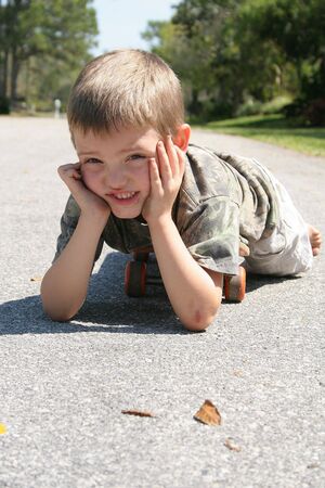 little boy laying on skateboardの写真素材